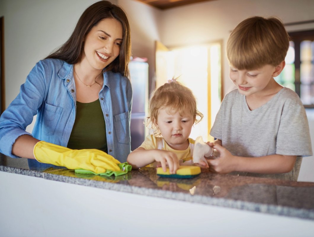 Moeder en twee kinderen poetsen samen het aanrecht in de keuken