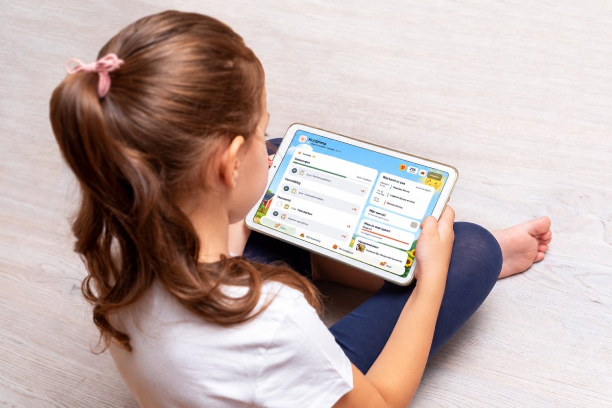 Meisje op de grond met een tablet waarop haar takenlijst voor vanmorgen, vanmiddag en vanavond staat